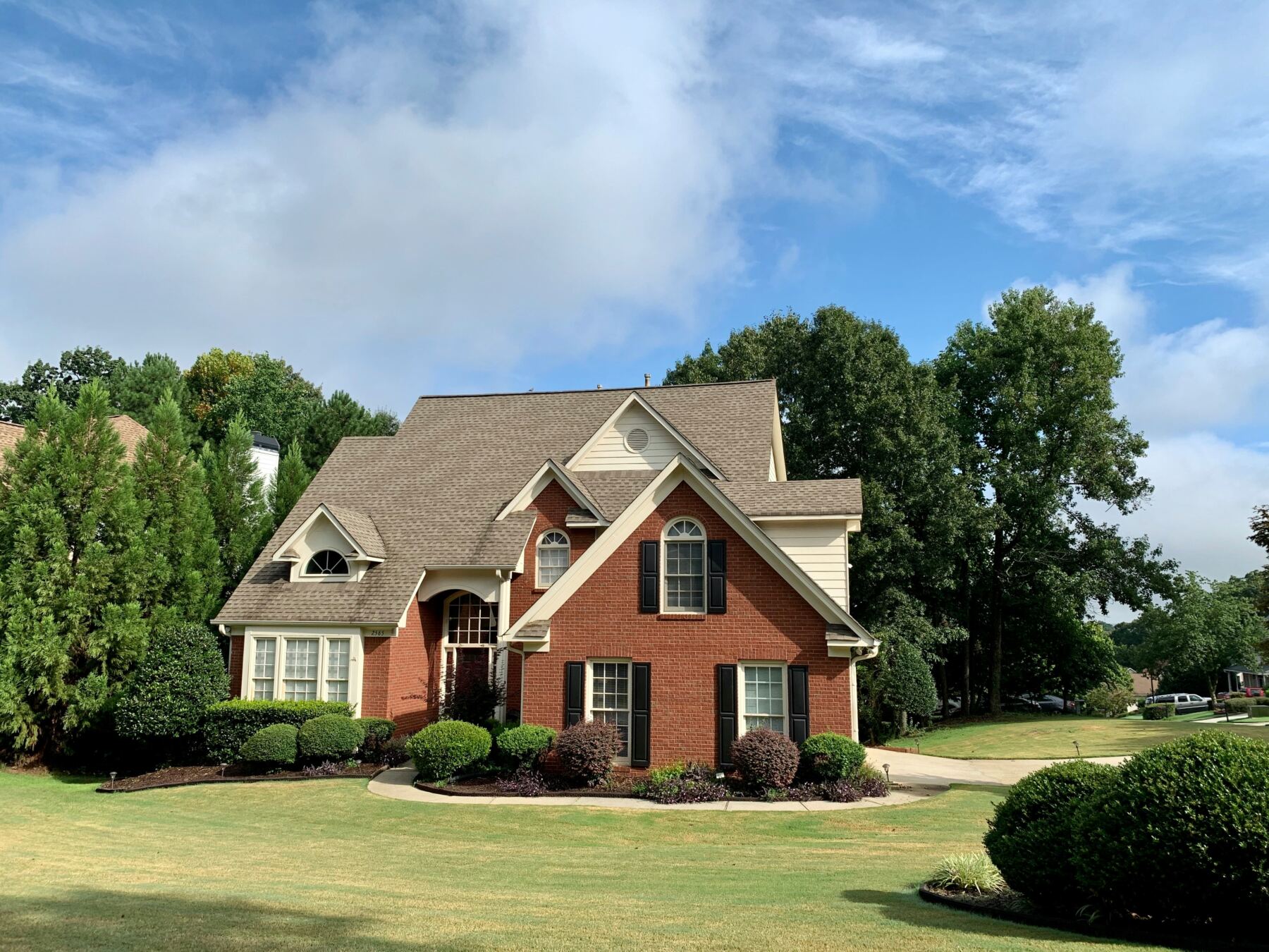Brick colonial home with a manicured lawn and mature trees